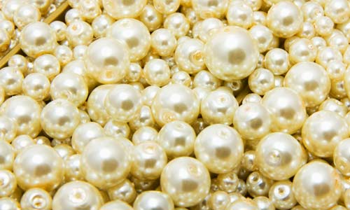 close-up of fake pearls with holes drilled, varying sizes