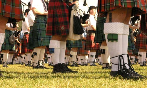 bagpipe players wearing kilts lineup on grass shoes and socks