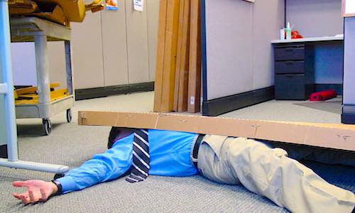 office fatigue guy in khakis and blue oxford knocked to floor by boxes and office work